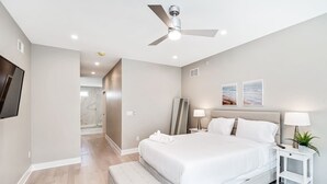 Una camera da letto moderna con un letto grande, comodini, una ventola a soffitto e opere d'arte alle pareti.