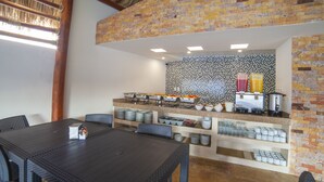 A dining area with a brick wall, a buffet counter, and a table with chairs. - Mayev Express (Santa María Huatulco)