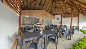 A restaurant with outdoor seating, a thatched roof, and a kitchen visible in the background. - Mayev Express (Santa María Huatulco)