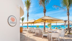 A poolside restaurant with outdoor seating, palm trees, and a view of the ocean. - Villa La Valencia Beach Resort & Spa Los Cabos (San José del Cabo)