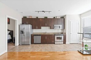 Modern kitchen with a central island, stainless steel appliances, and a glass shelf unit.