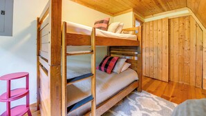 A bunk bed with a wooden headboard, a pink chair, and a wooden wardrobe in a room with wooden flooring and walls. - Sip, Soak & Unwind: Waynesville Cabin w/ Hot Tub (Waynesville)