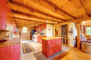 Een houten chalet van binnen met een keuken, een wasmachine en een eethoek.