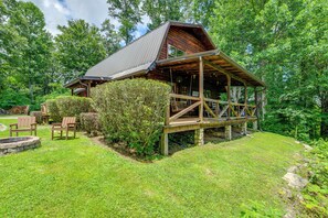 A rustic cabin with a wooden deck and a fire pit area.