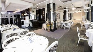 A modern hotel lobby with round tables, white chairs, and a central column with a floral arrangement. - Royal Garden Hotel Beirut (Beirut)