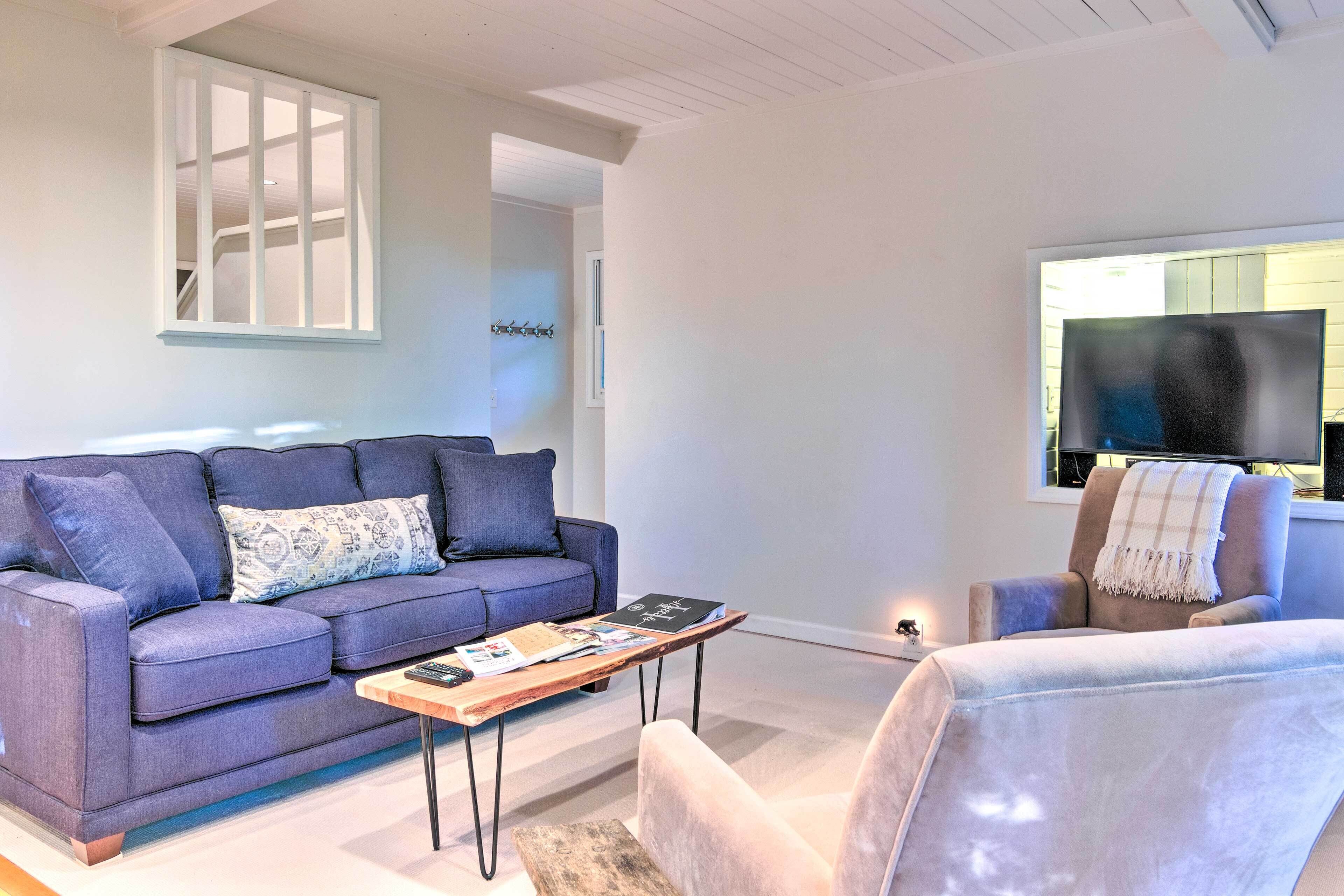A modern living room with a sofa, armchair, coffee table, and a TV.