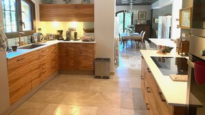 Una cocina moderna con armarios de madera, un lavamanos de acero inoxidable y un comedor con mesa y sillas.