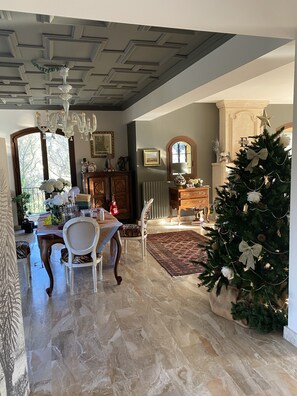 A spacious dining area with a marble floor, a chandelier, and a Christmas tree.