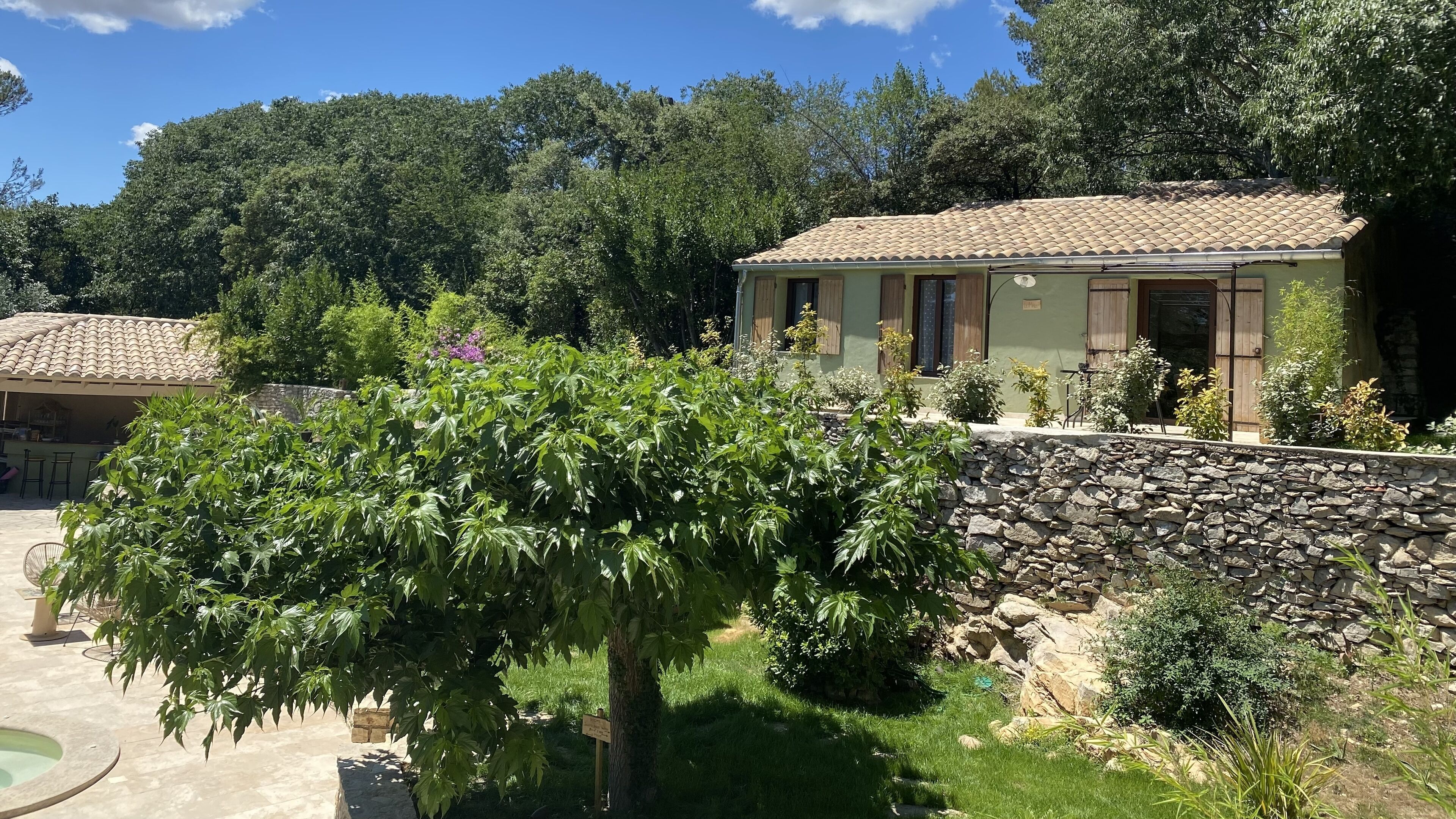 A villa with a stone wall, a patio, and a garden.