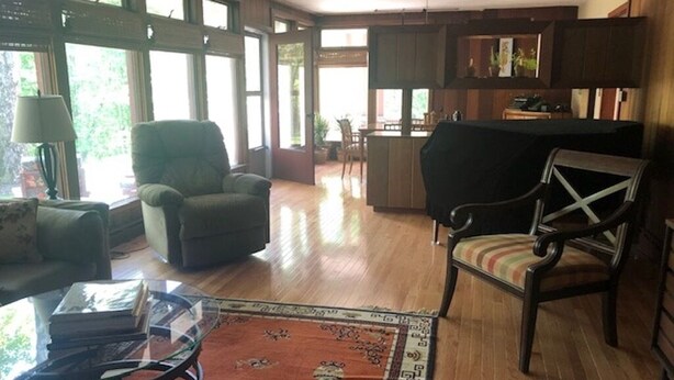 Un vaste espace de vie doté d’un plancher en bois, d’une table basse en verre, d’un tapis à motifs et d’un fauteuil confortable.