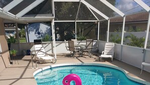 A swimming pool with a pink flamingo float, surrounded by lounge chairs and a covered patio area. - Newly remodeled, all new furniture, beaches, shopping, restaurants, golf, tennis (Venice)