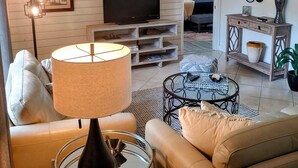 A living room with a TV, sofa, and lamp. - Newly remodeled, all new furniture, beaches, shopping, restaurants, golf, tennis (Venice)