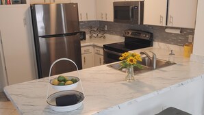 A modern kitchen with a marble countertop, stainless steel appliances, and a built-in sink. - Newly remodeled, all new furniture, beaches, shopping, restaurants, golf, tennis (Venice)