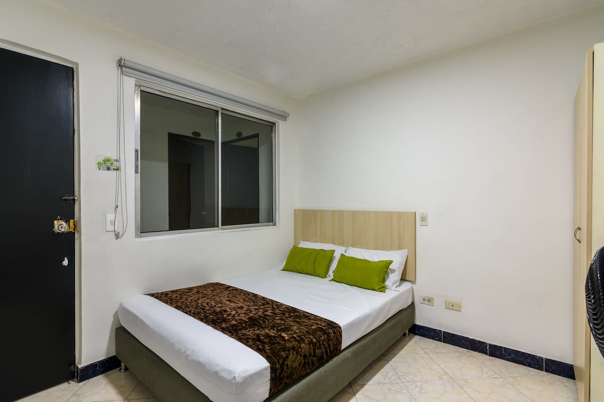 Una camera da letto con un letto, una finestra, una porta e un interruttore a parete.
