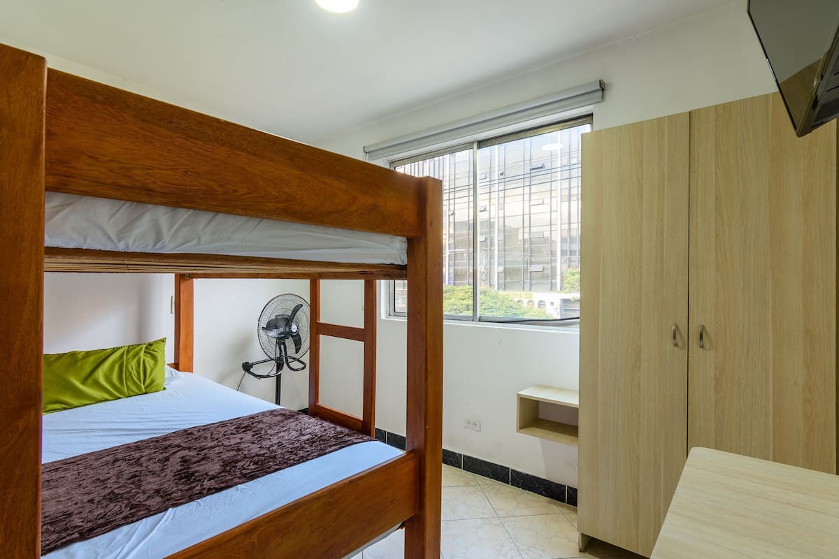 Un letto a castello con una ventola, un'armadio in legno e una finestra con vista.