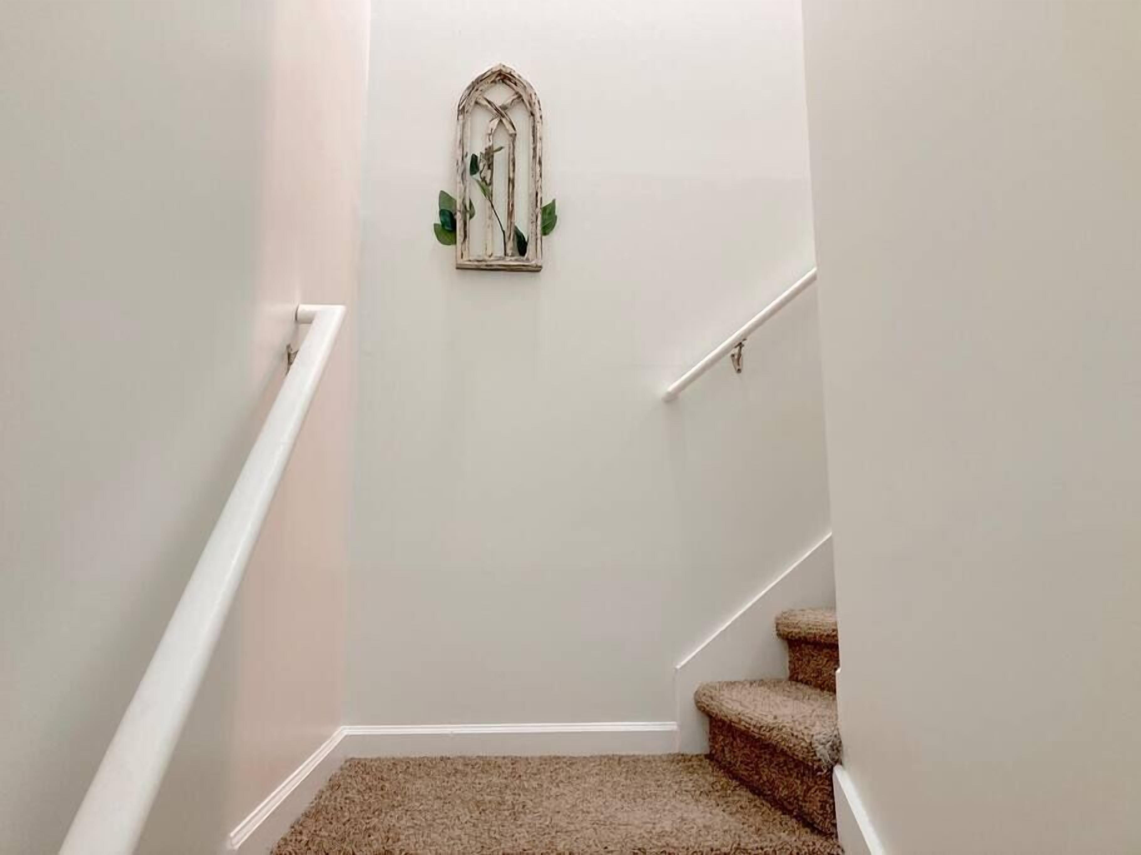 A staircase with a carpeted landing and a wall-mounted decorative piece.