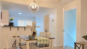 A dining area with a table set for four, a laptop, and a vase with flowers. - Bright Townhome with THREE KING-SIZE beds (Cartersville)