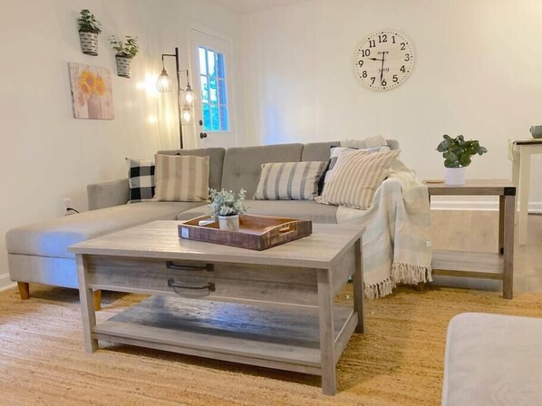 Un salon avec un canapé, une table basse et une horloge au mur.