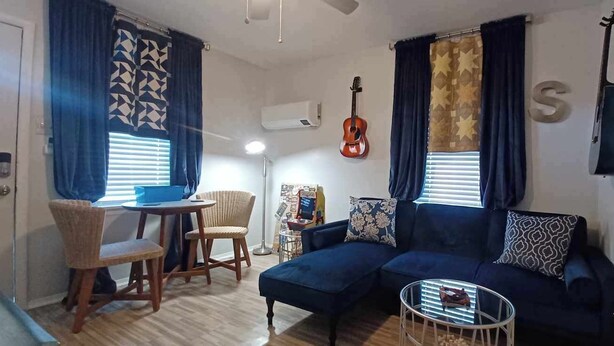 A living room with a blue sofa, a small round table, a guitar, and a window with patterned curtains. - Blues Alley Downtown Memphis  (Memphis)