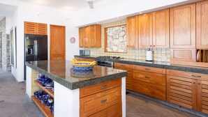A modern kitchen with wooden cabinets, a granite countertop, and a built-in stove.