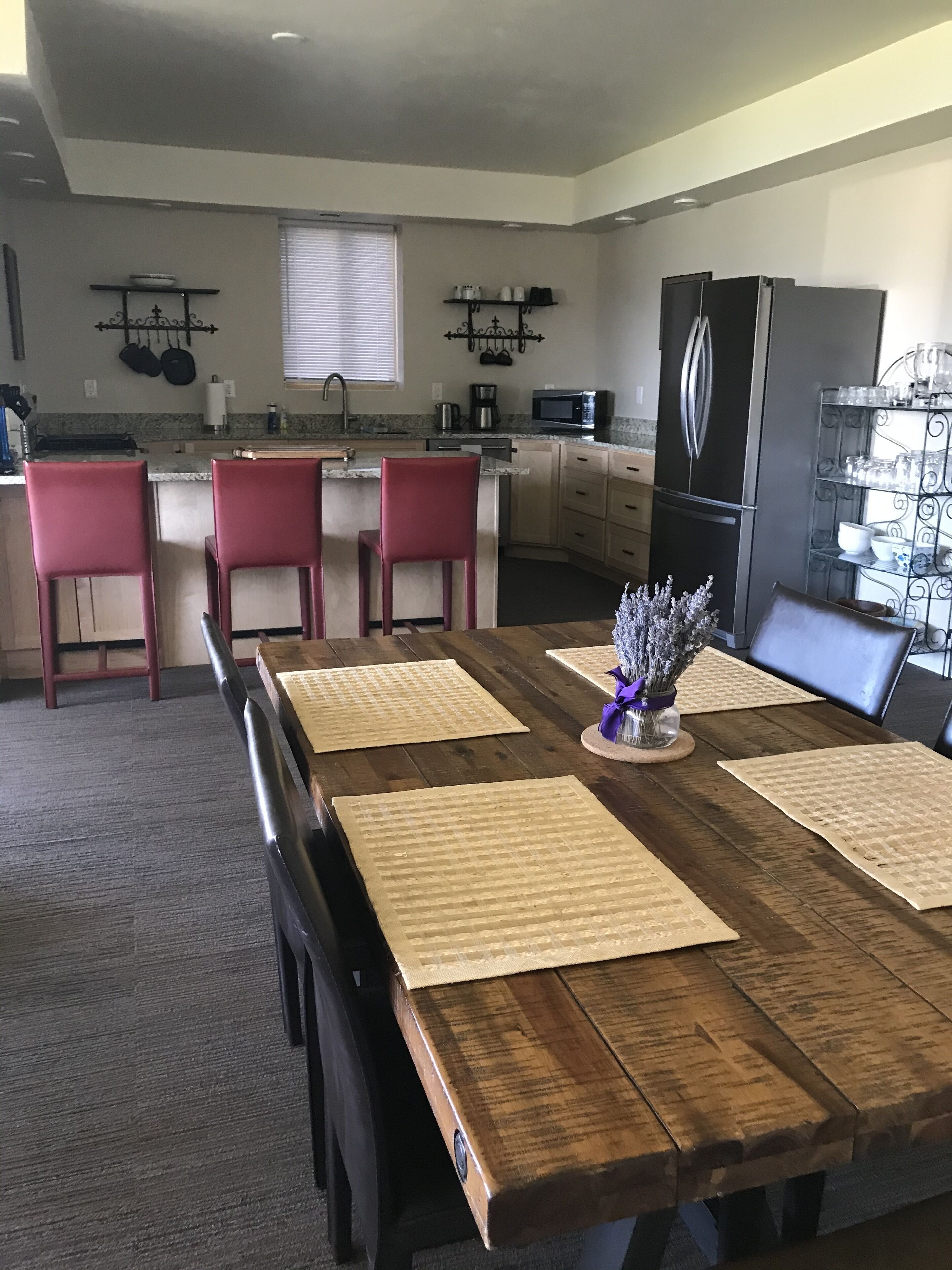 Un coin repas avec une table en bois, des chaises rouges et une cuisine en arrière-plan.