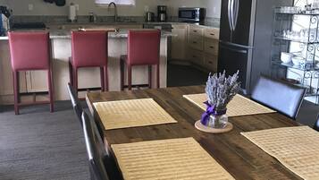Un coin repas avec une table en bois, des chaises rouges et une cuisine en arrière-plan.