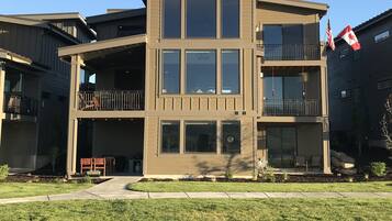 A modern two-story building with a flat roof, large windows, and a balcony.
