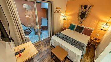 Een hotelkamer met een bed, een kleine tafel, een bankje, een stoel, een lamp en uitzicht.