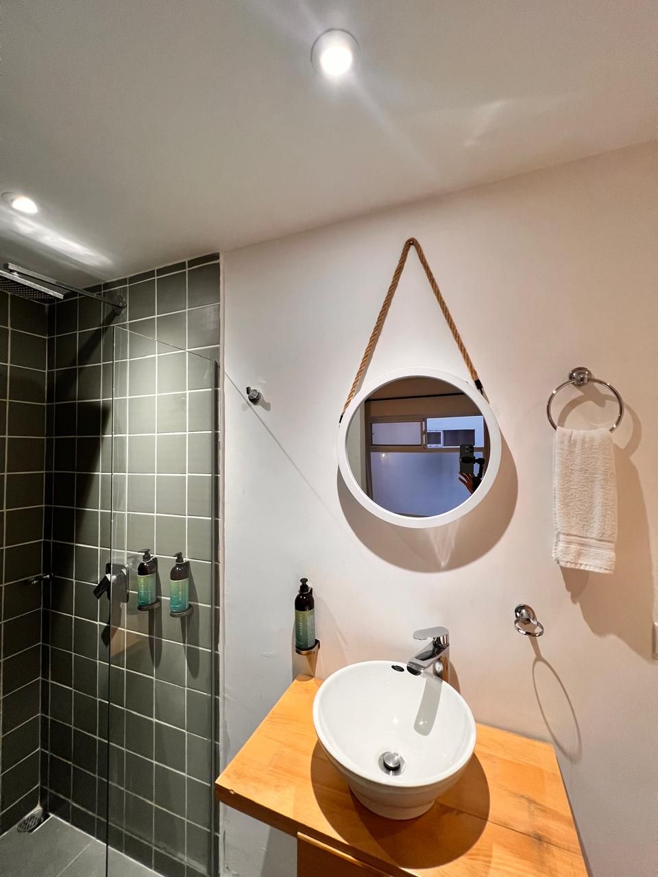 A bathroom with a round mirror, a sink, and a towel rack.