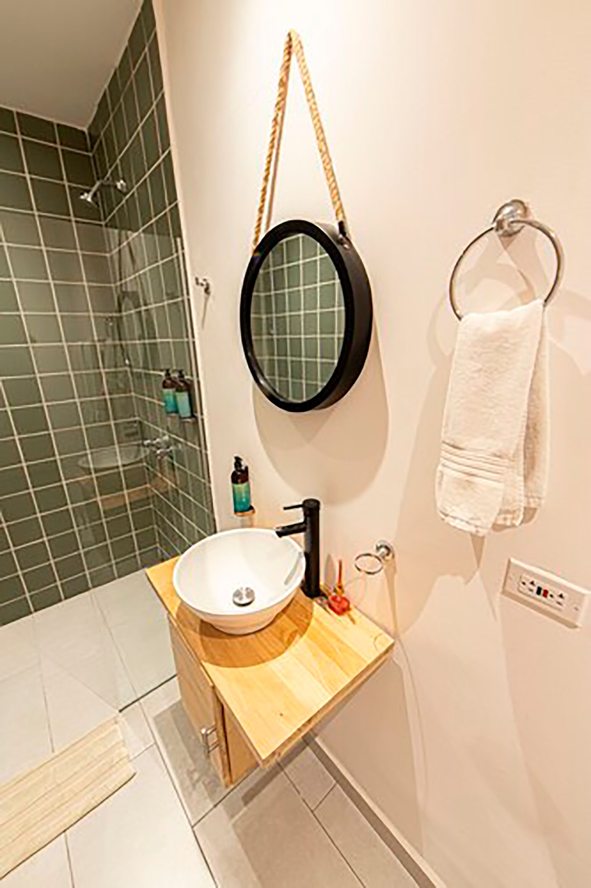 A bathroom with a wooden vanity, a round mirror, and a towel ring.