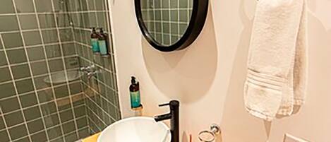 A bathroom with a wooden vanity, a round mirror, and a towel ring.
