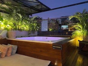 A wooden deck with a hot tub labeled 'Zona Humeda' and a view of a cityscape at dusk. - Vivus La Martina Boutique Hotel (Medellín)