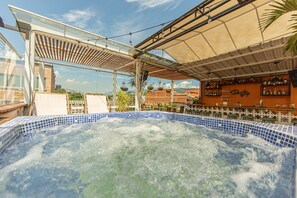 A hot tub with a tiled edge, surrounded by outdoor furniture and a shaded area with hanging lights. - Vivus La Martina Boutique Hotel (Medellín)