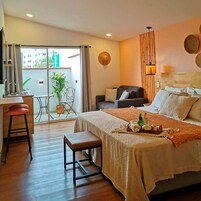 Ein Hotelzimmer mit Bett, Schreibtisch, Stuhl und einem Balkon mit Blick auf Gebäude.