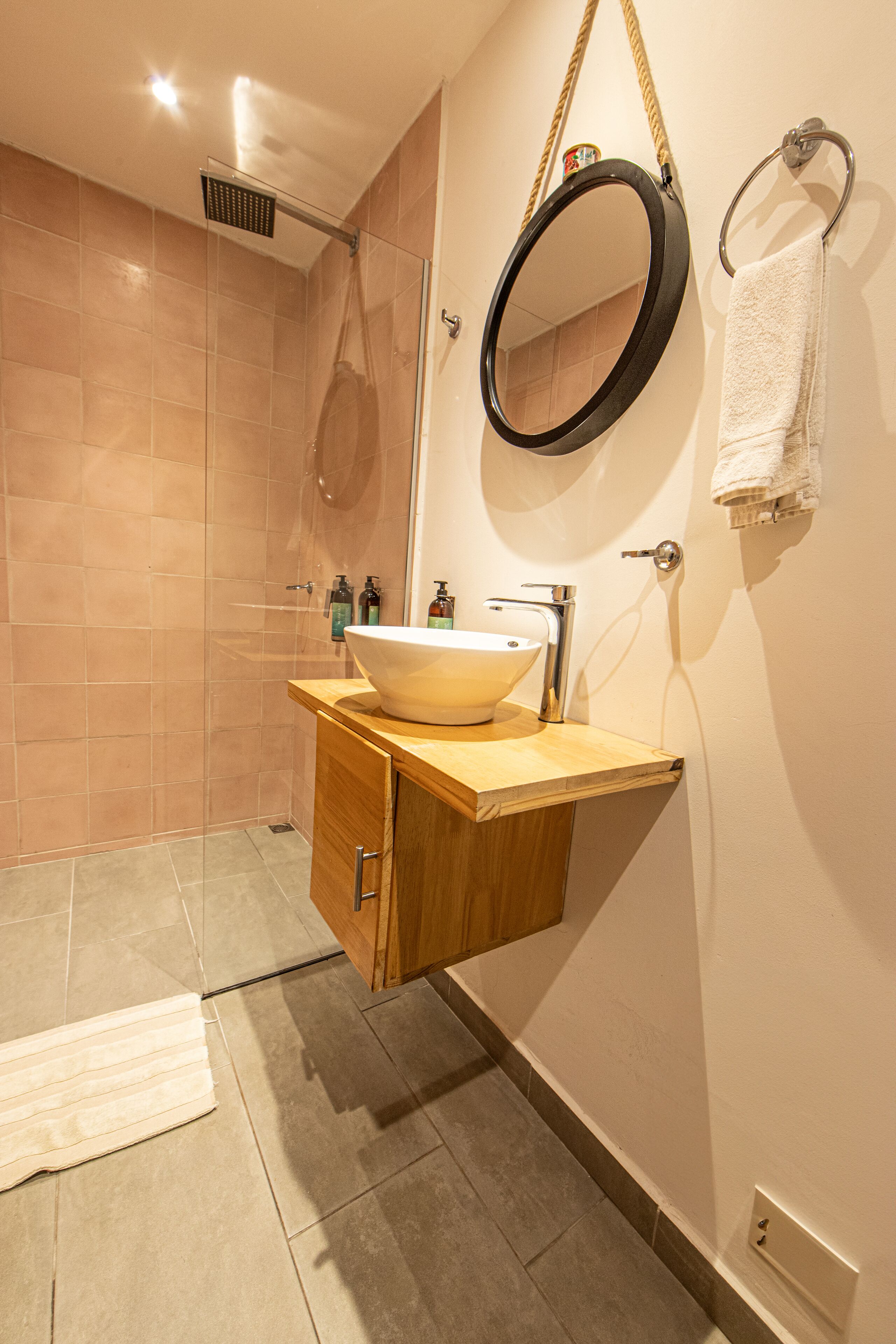 A bathroom with a wooden vanity, a large mirror, a sink, and a shower.