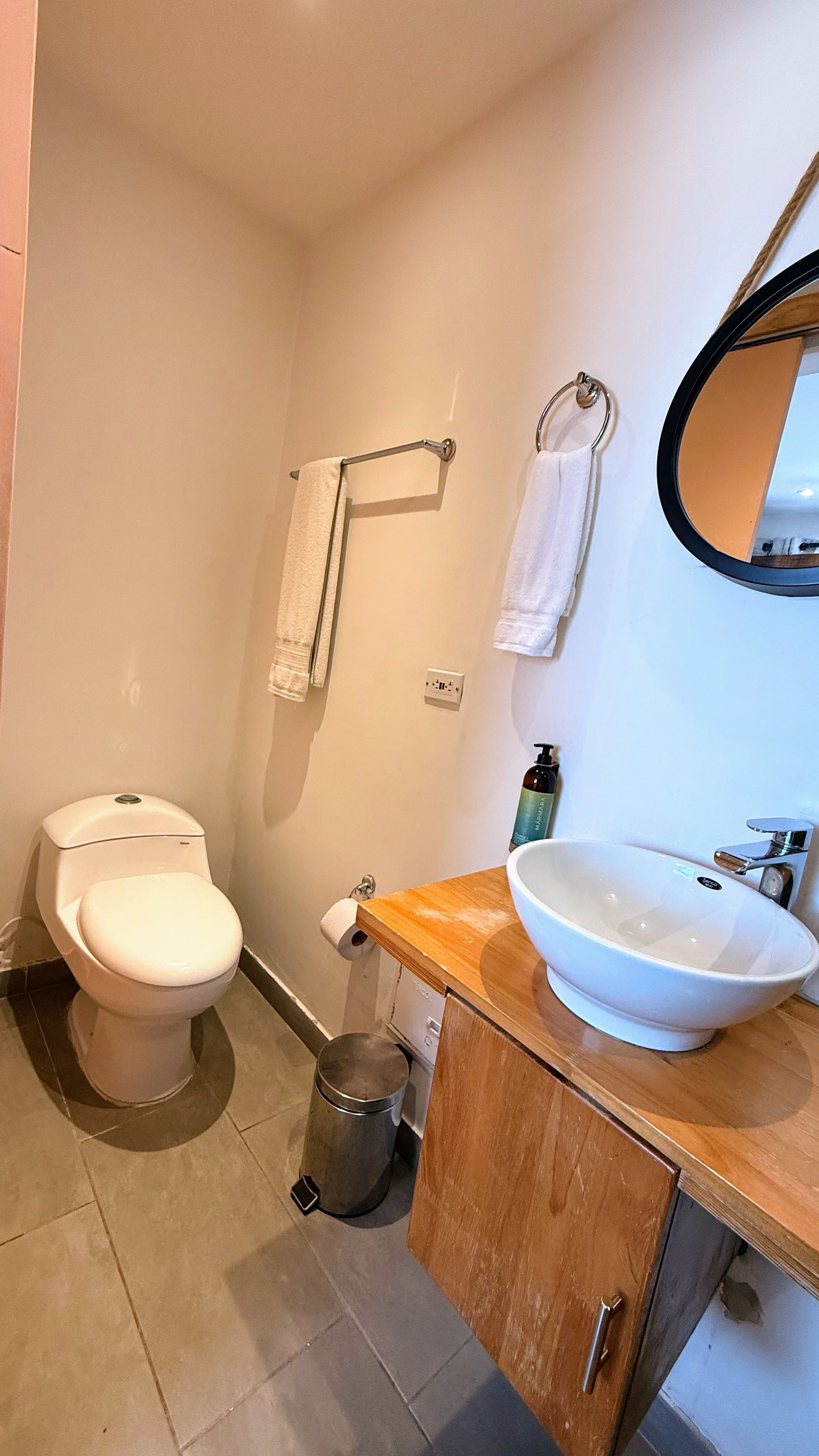A bathroom with a toilet, a sink, a mirror, and a towel rack.