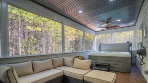 A modern outdoor living area with a sectional sofa, a hot tub, and a ceiling fan. - Hot tub-Interactive family gaming-Game room! (Helen)