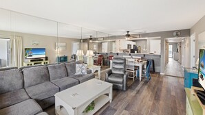 Ein großzügiges Wohnzimmer mit grauem Sofa, einem weißen Couchtisch und einem Essbereich mit Tisch und Stühlen.