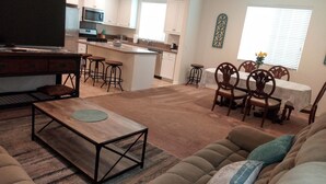 A living room with a wooden coffee table, a sofa, and a dining area with a table and chairs. - LOWEST PRICE OF THE SEASON! 
NEW and AMAZING! Spacious! DOD, Military Welcome! (Imperial Beach)