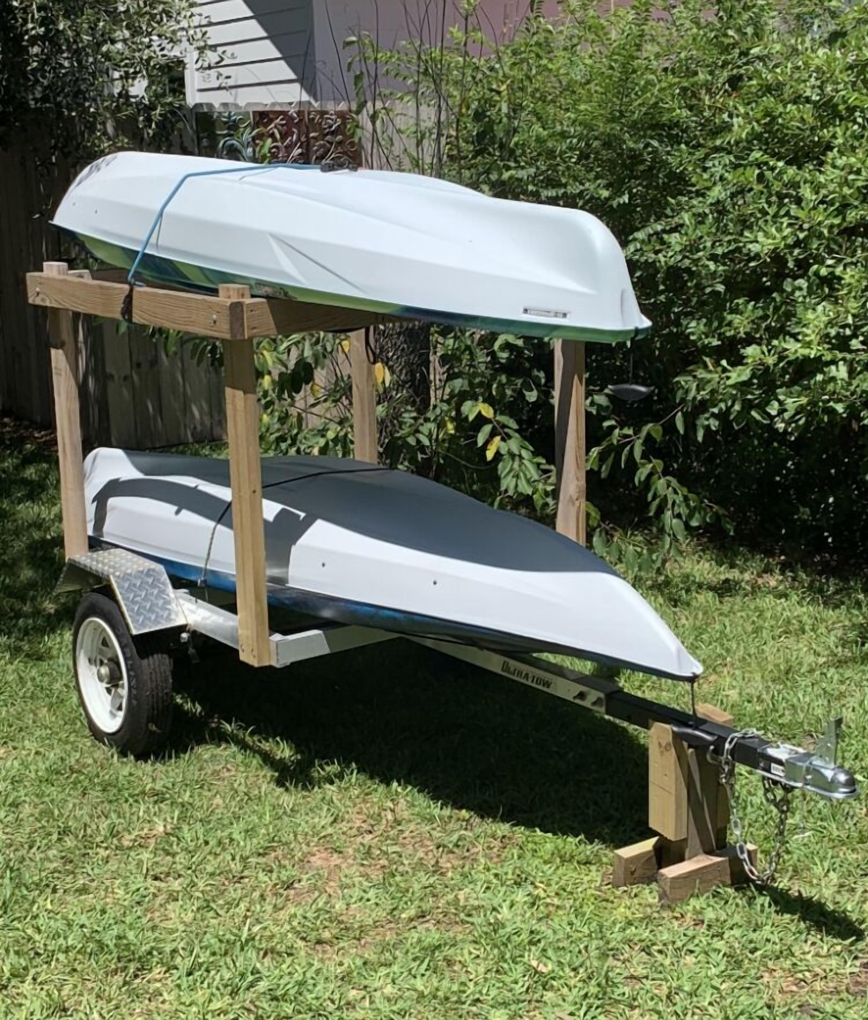 A boat trailer with a boat on it, secured with a blue tarp.