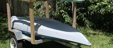 A boat trailer with a boat on it, secured with a blue tarp.