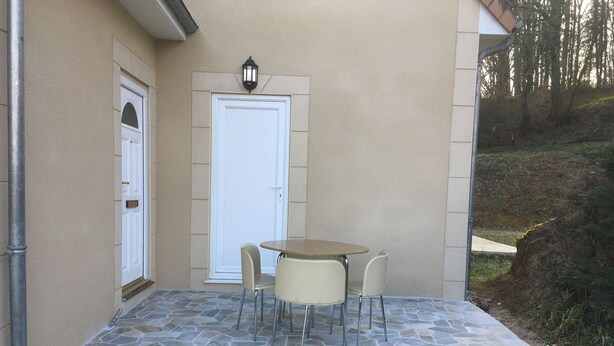 A patio with a stone floor, a round table, and four chairs.