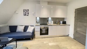 A compact living space with a kitchenette, a sofa, a small table, and a microwave. - Remarkable 1-Bed Apartment in Slough (Slough)