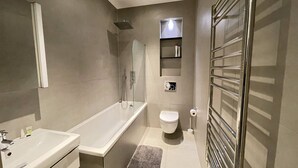 A modern bathroom with a bathtub, toilet, and glass shower enclosure. - Remarkable 1-Bed Apartment in Slough (Slough)
