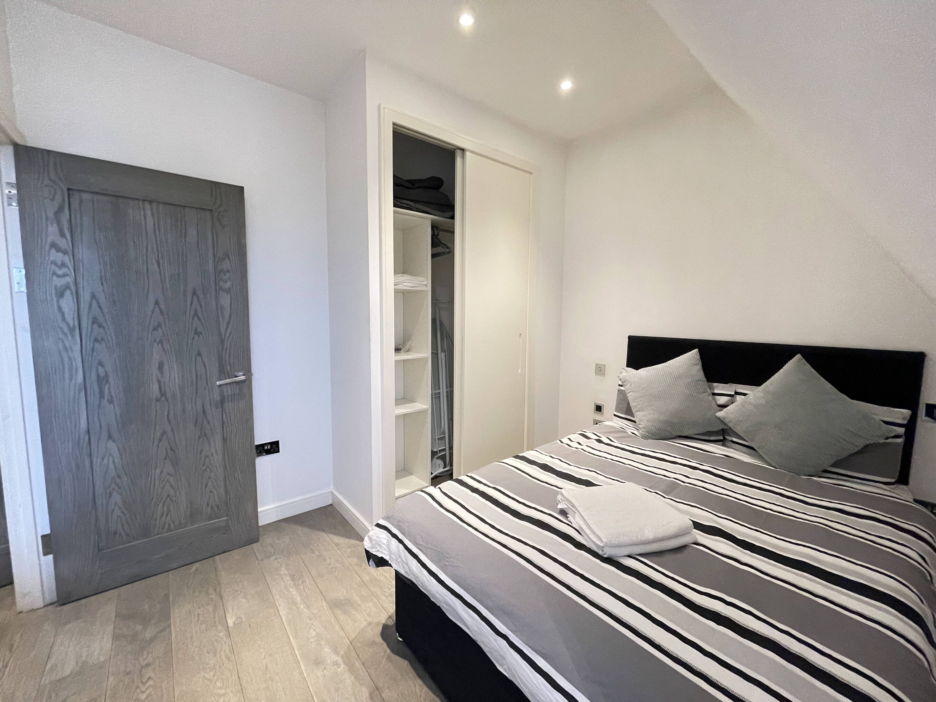 A bedroom with a bed, a wardrobe, and a walk-in closet.