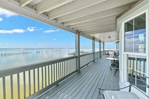 A covered deck with a view of the ocean and a dock in the distance.
