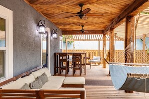 A covered outdoor seating area with wooden furniture, a hammock, and ceiling fans. - The Bungalow on Wilton Drive.  Upscale, Unique House with Huge Front Porch! (Wilton Manors)