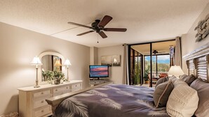 Quarto com cama, penteadeira, televisão e ventoinha no teto.