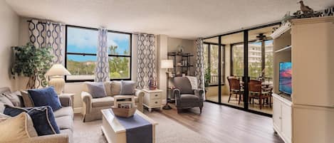 A spacious living room with a sofa set, a coffee table, and a dining area with chairs and a TV.