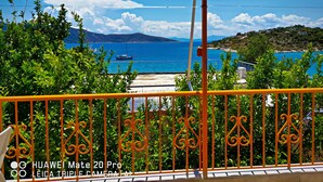 A balcony with a view of a coastal area, including a boat on the water and distant hills. - Iliaktis Xenios Zeus  (Νήσοι)